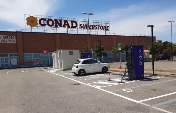 Auto in ricarica all'esterno di un supermercato Conad 